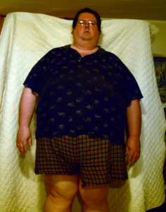 large man standing in front of white sheet staring at camera