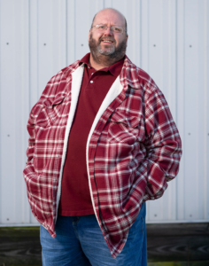 Man smiling at camera in red flannel shirt