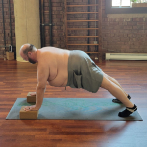 large man doing push-ups with yoga blocks